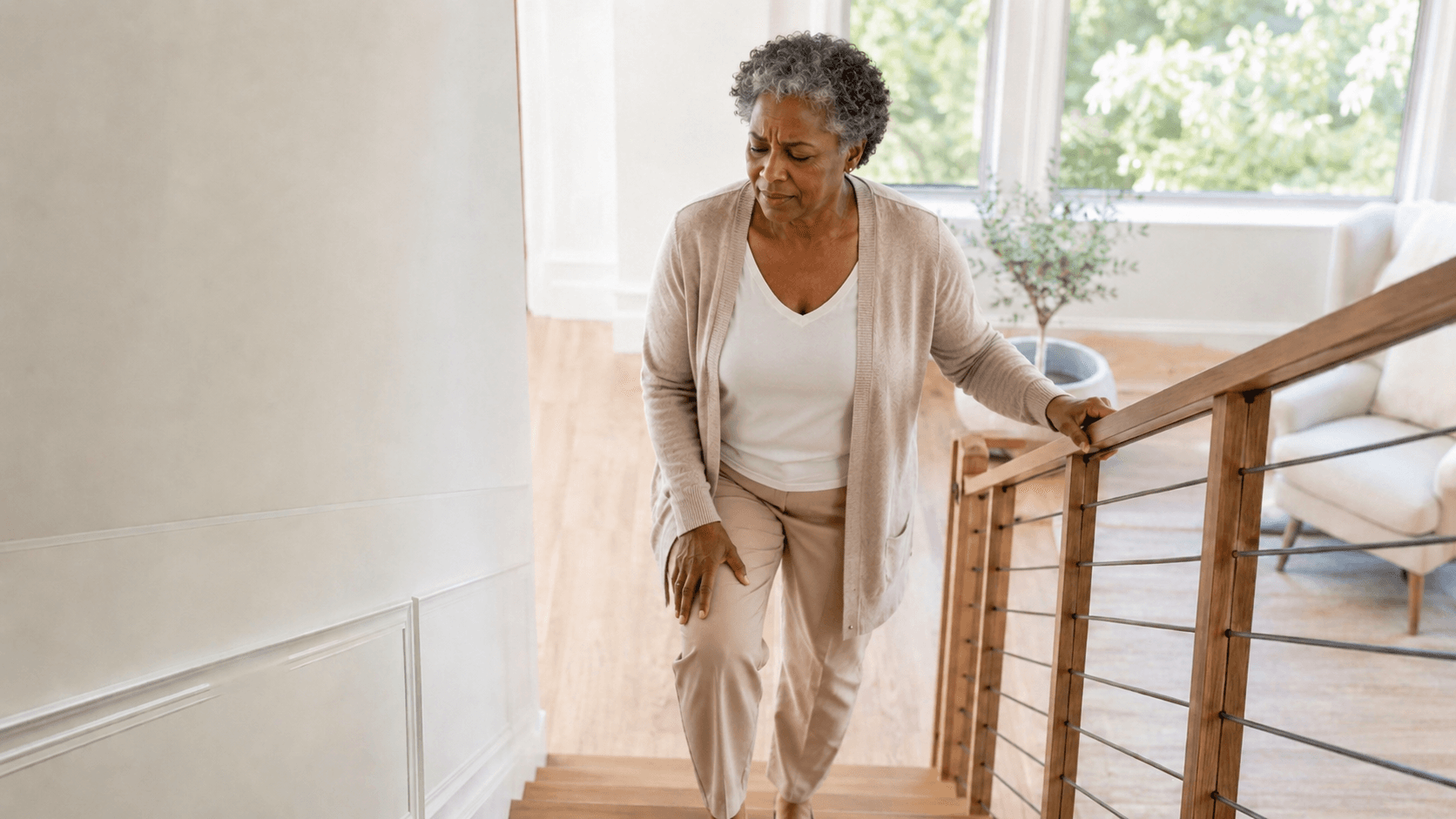 A woman pausing on the stairs, holding her knee