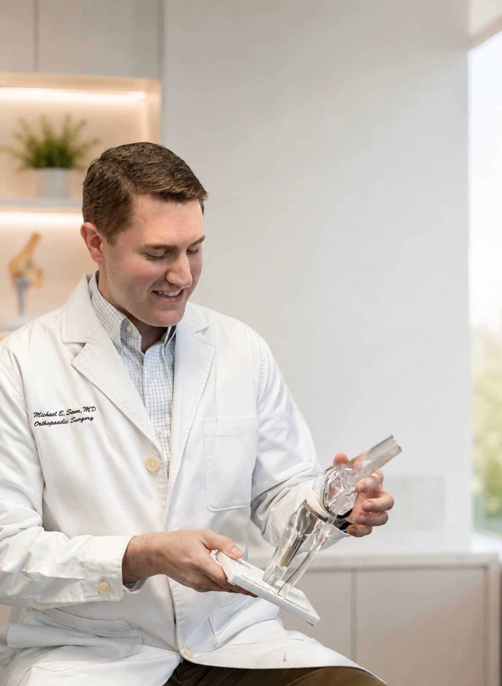 Michael E. Seem, MD examining a knee replacement model in his clinic